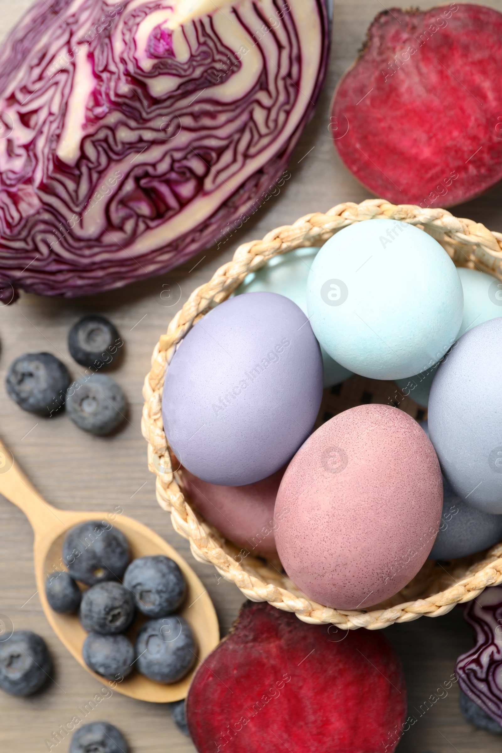 Photo of Colorful Easter eggs painted with natural dyes and ingredients on wooden table, above view