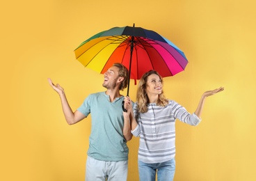 Photo of Couple with rainbow umbrella on color background