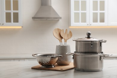 Photo of Set of stainless steel cookware and kitchen utensils on white table indoors, space for text