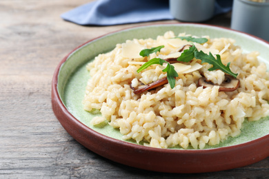 Photo of Delicious risotto with cheese and mushrooms on wooden table, closeup