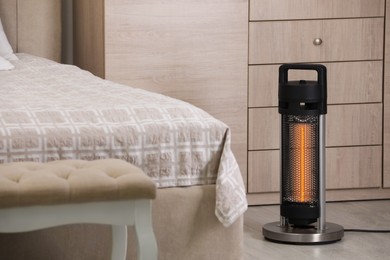 Photo of Modern infrared heater on floor in bedroom