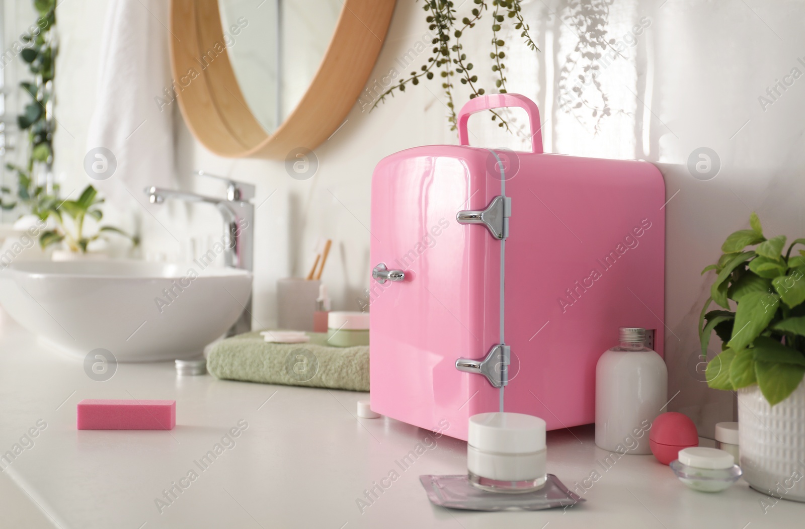 Photo of Cosmetics refrigerator and skin care products on white countertop in bathroom