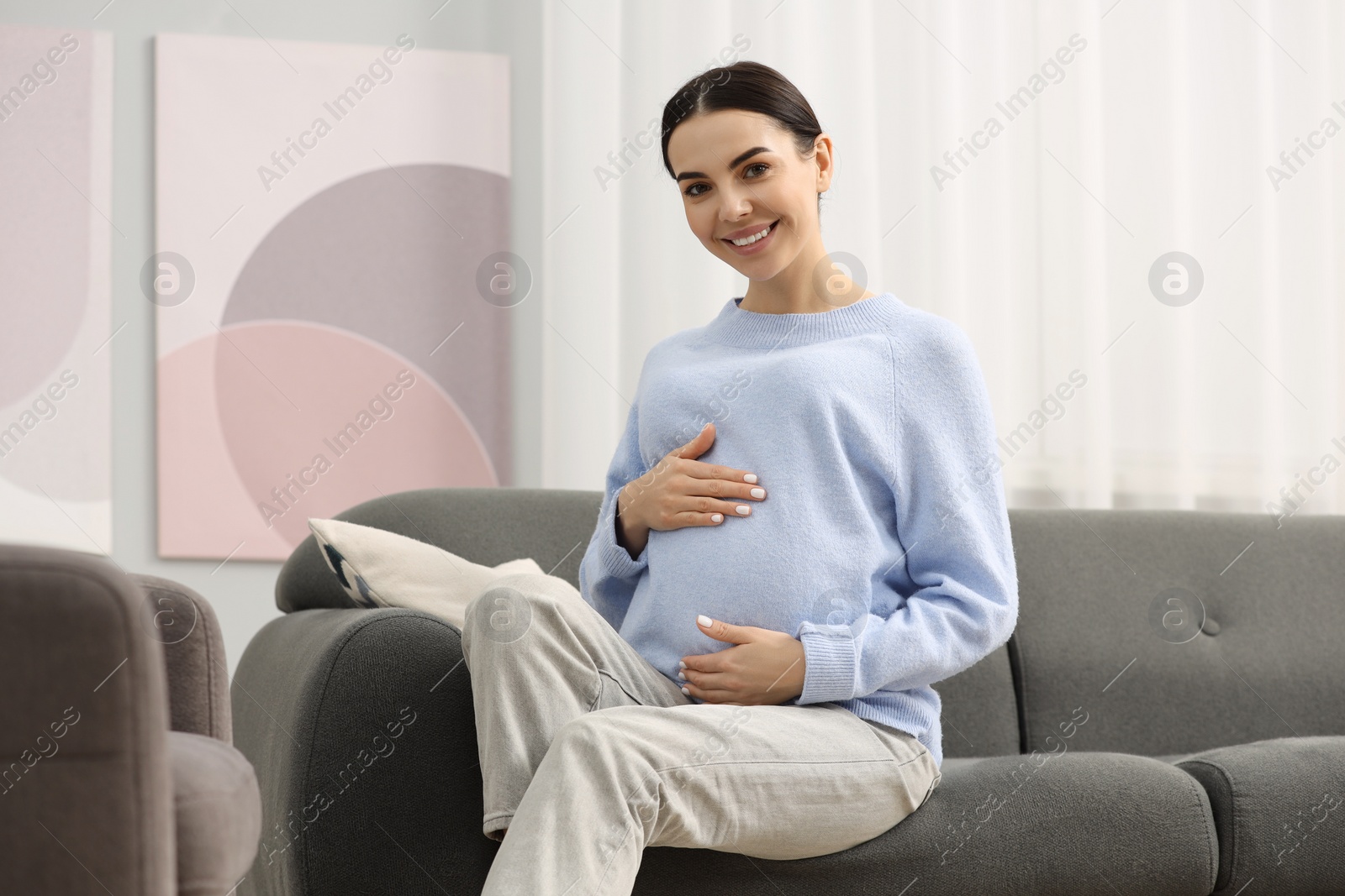 Photo of Happy pregnant woman on sofa at home