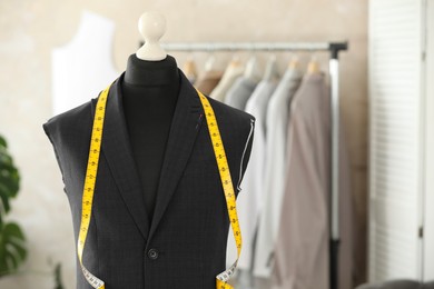 Mannequin with unfinished suit jacket and measuring tape in tailor shop, space for text