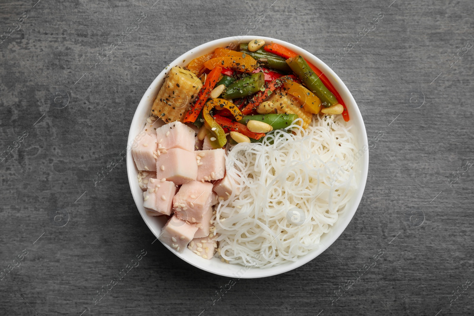 Photo of Tasty cooked rice noodles with chicken and vegetables on grey table, top view