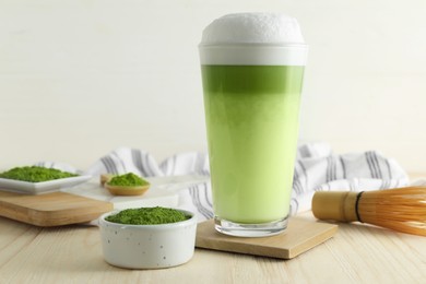 Photo of Glass of fresh matcha latte and green powder on wooden table