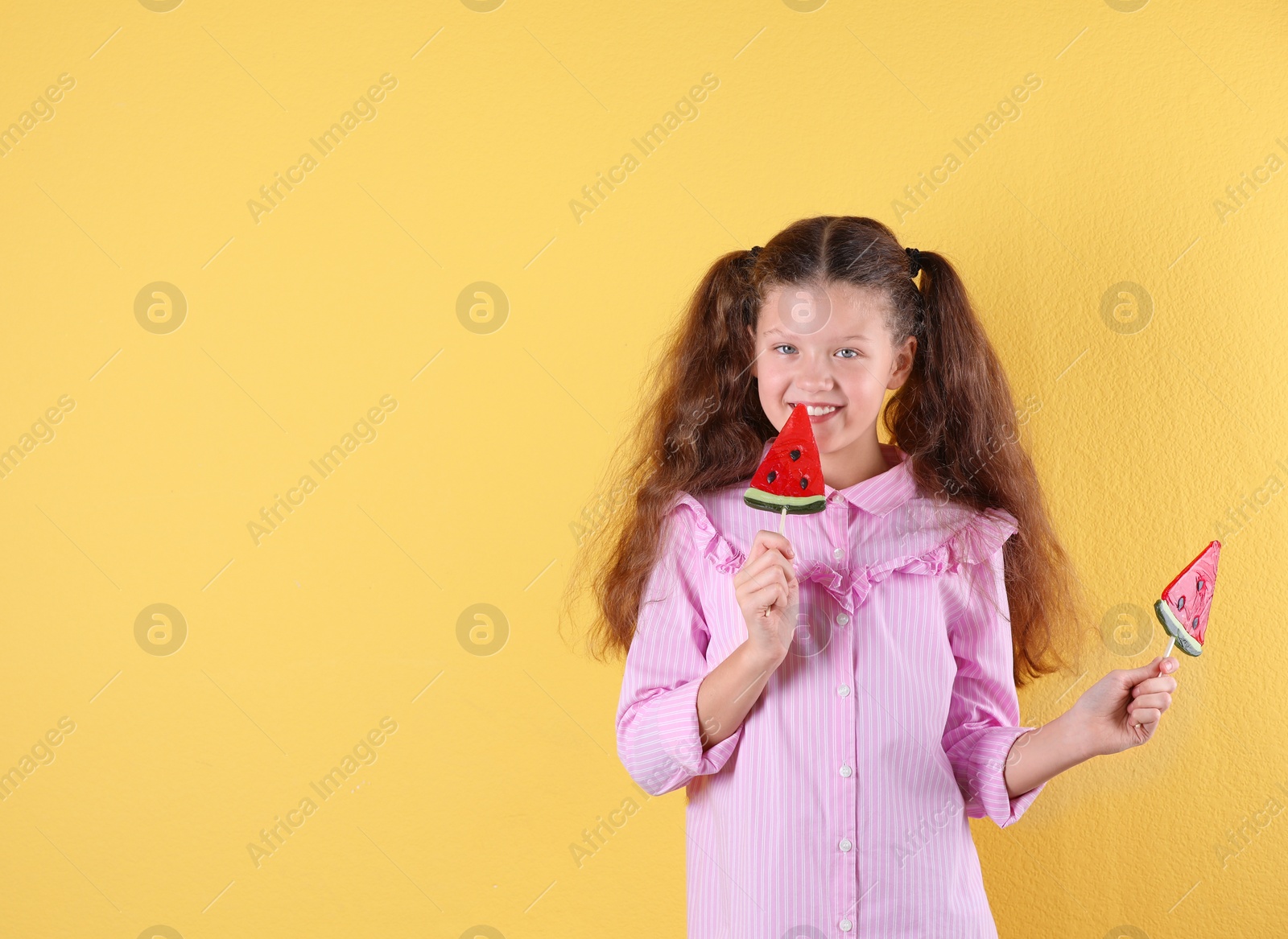 Photo of Little girl with candies on color background. Space for text