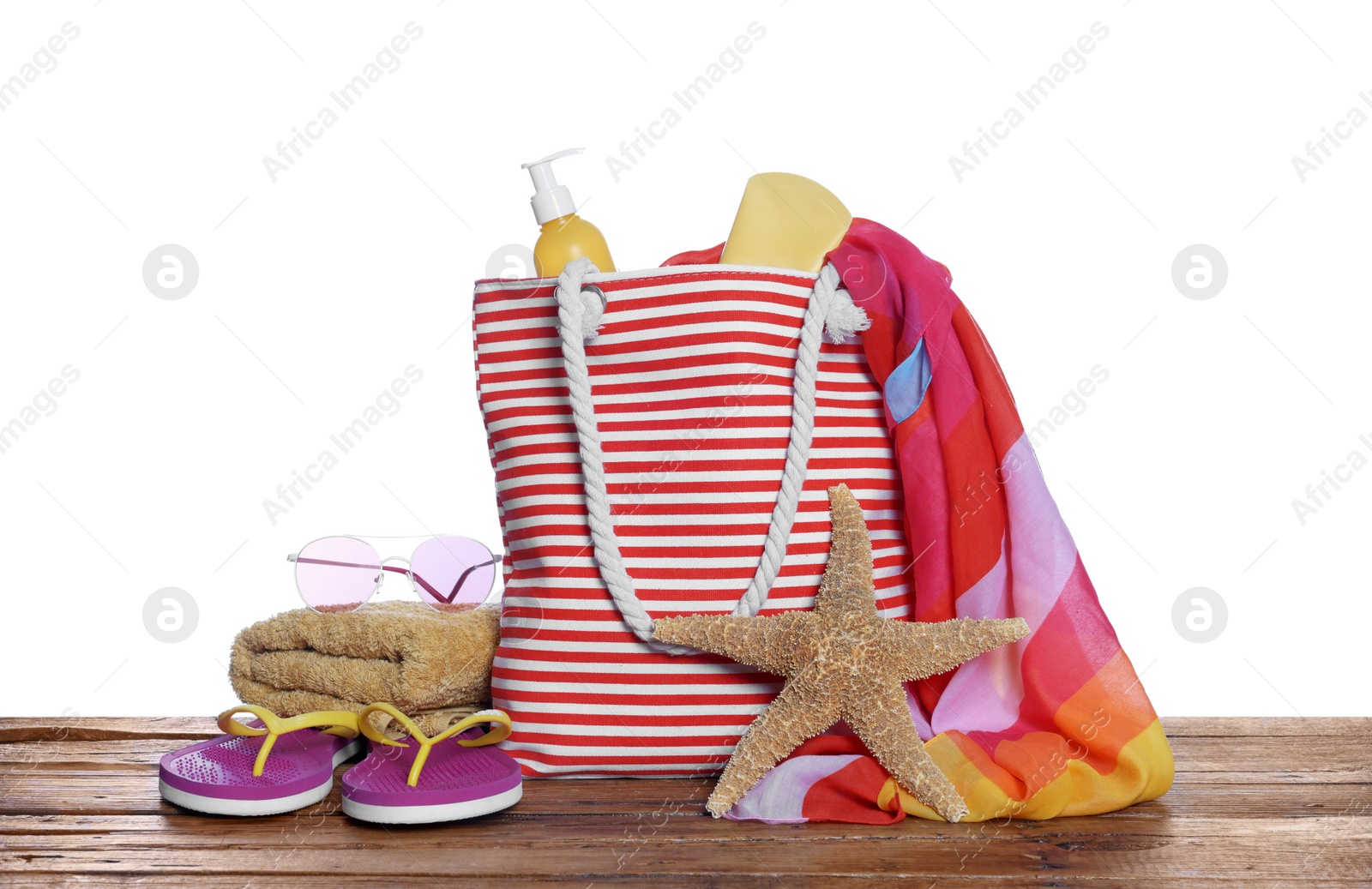 Photo of Stylish bag, starfish and other beach accessories on wooden table against white background