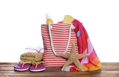 Stylish bag, starfish and other beach accessories on wooden table against white background