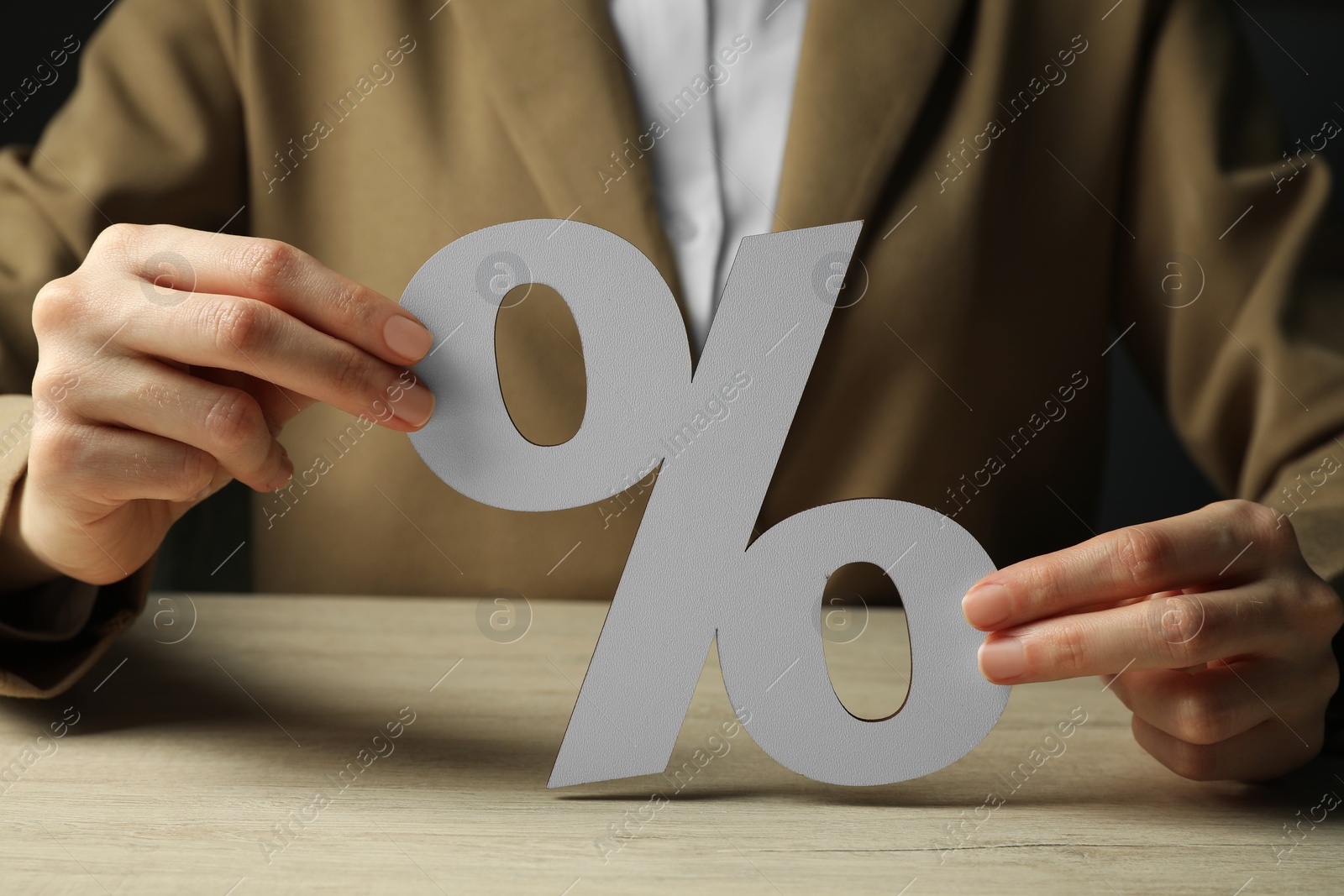 Photo of Woman holding percent sign at wooden table, closeup