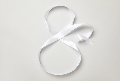 Number 8 made of white ribbon on light grey background, top view. International Women's day