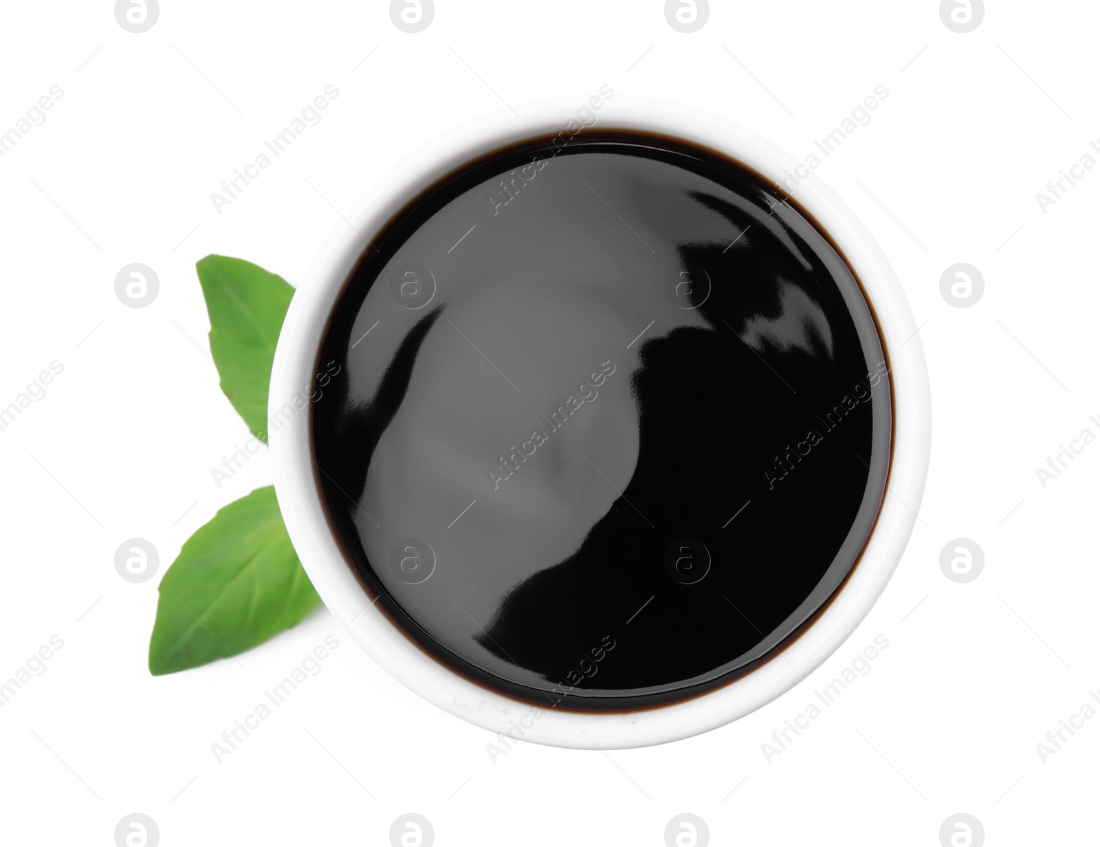 Photo of Balsamic glaze and basil leaves on white background, top view