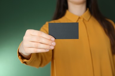 Photo of Woman holding black business card on green background, closeup