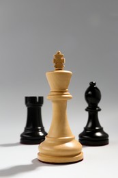 Photo of Different chess pieces against light background, focus on white king