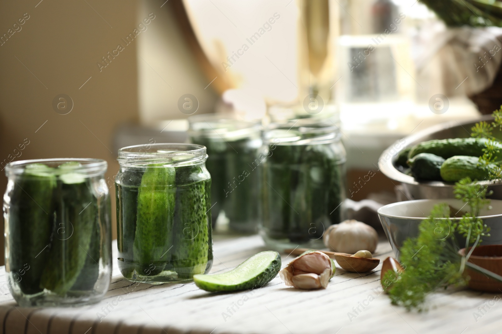 Photo of Glass jars with fresh cucumbers and other ingredients on table indoors. Canning vegetables