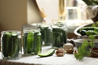 Glass jars with fresh cucumbers and other ingredients on table indoors. Canning vegetables