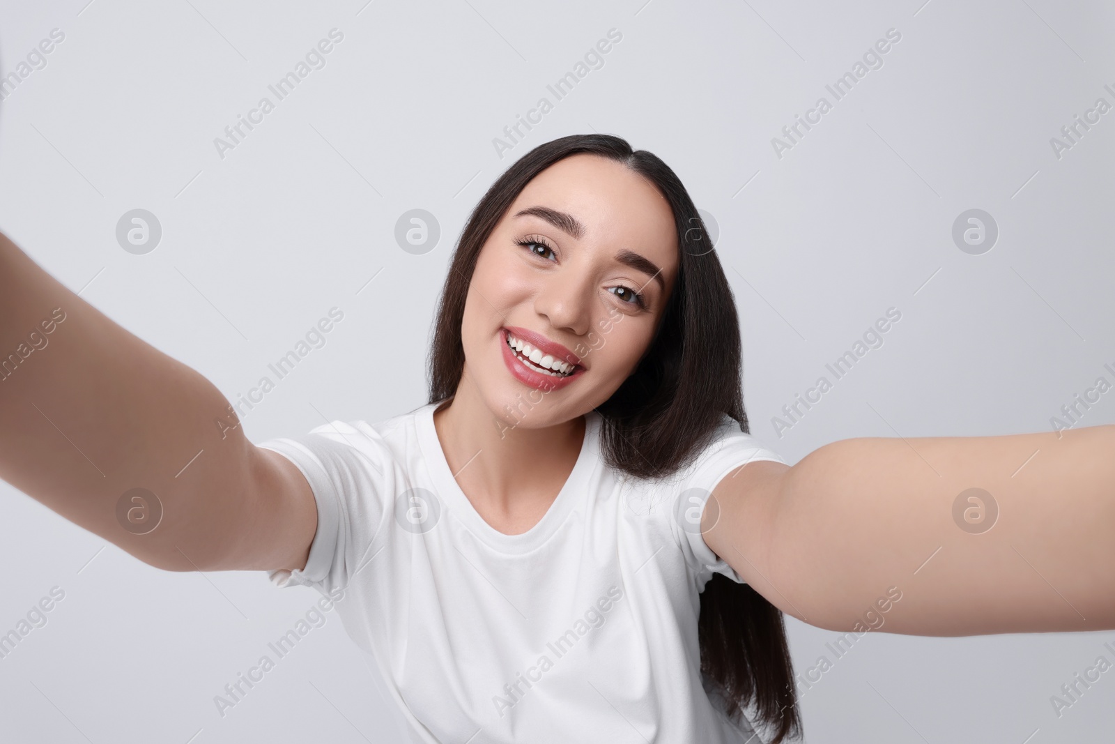 Photo of Smiling young woman taking selfie on white background