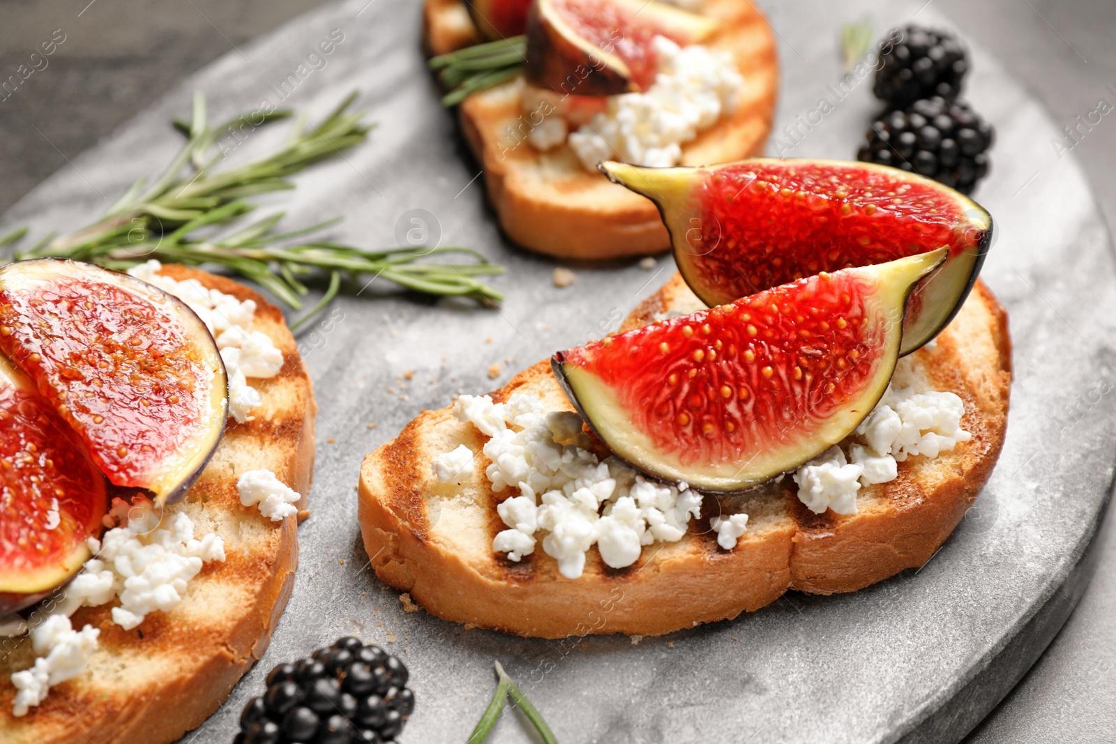 Photo of Bruschettas with ripe figs and cheese served on board, closeup