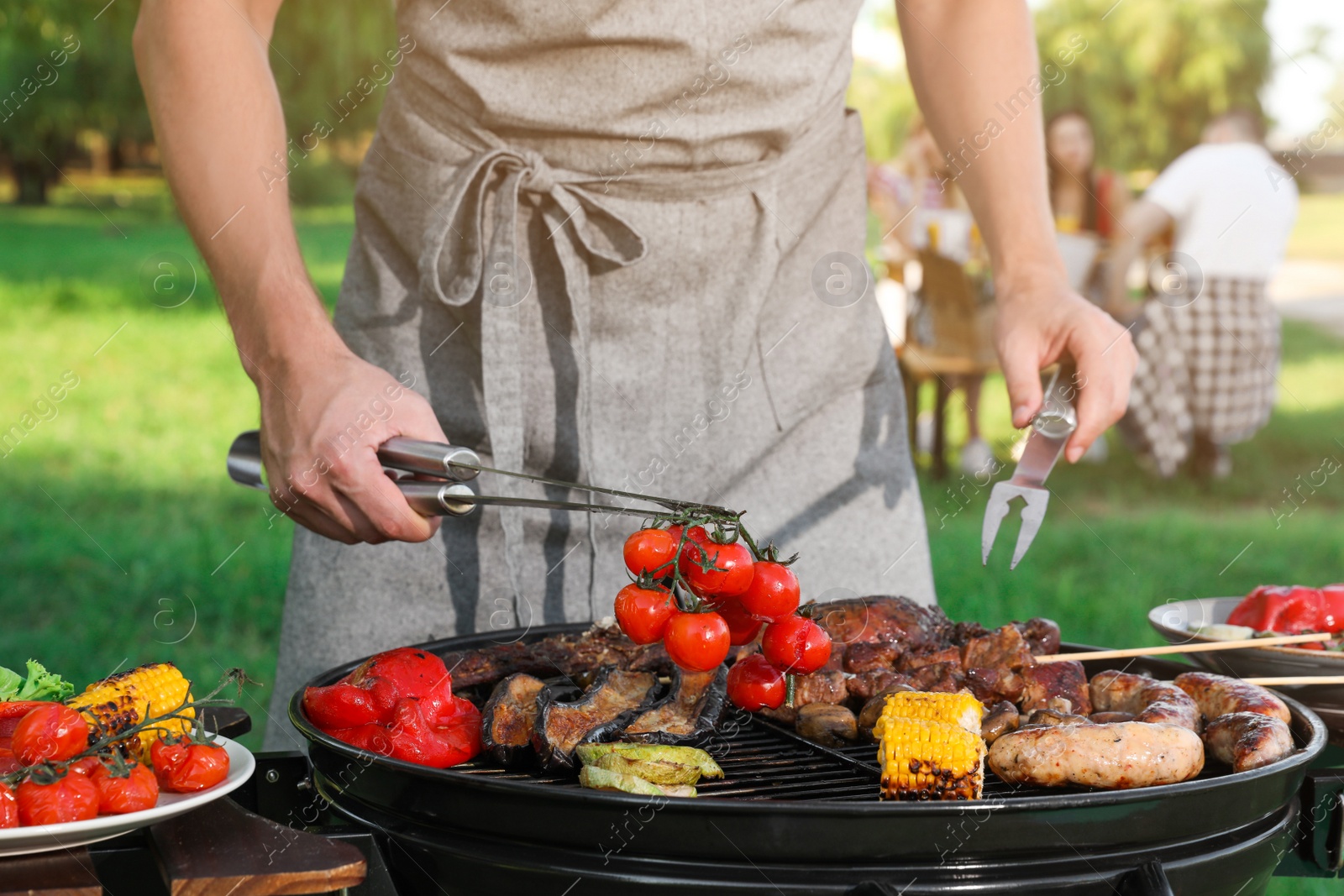 Photo of Man cooking meat and vegetables on barbecue grill outdoors, closeup