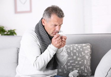Man suffering from cough and cold on sofa at home