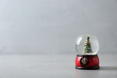 Snow globe with Christmas tree on grey table, space for text