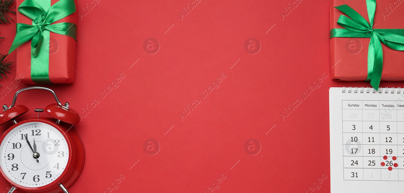Photo of Paper calendar with marked Boxing Day date, alarm clock and gifts on red background, flat lay. Space for text