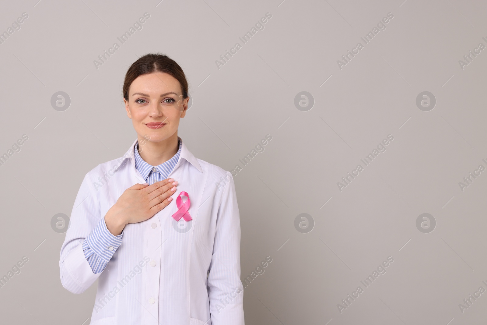 Photo of Mammologist with pink ribbon on grey background, space for text. Breast cancer awareness