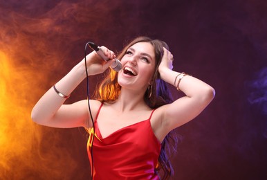 Photo of Emotional woman with microphone singing in color lights