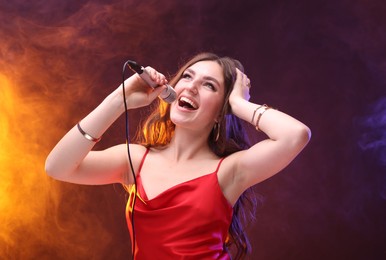 Emotional woman with microphone singing in color lights