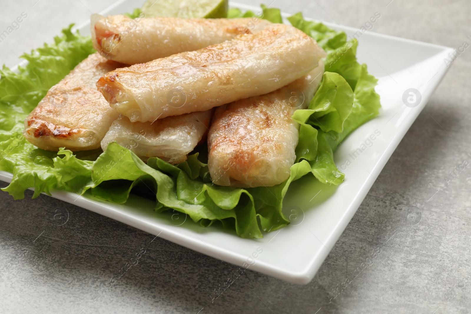 Photo of Delicious fried spring rolls on grey table, closeup