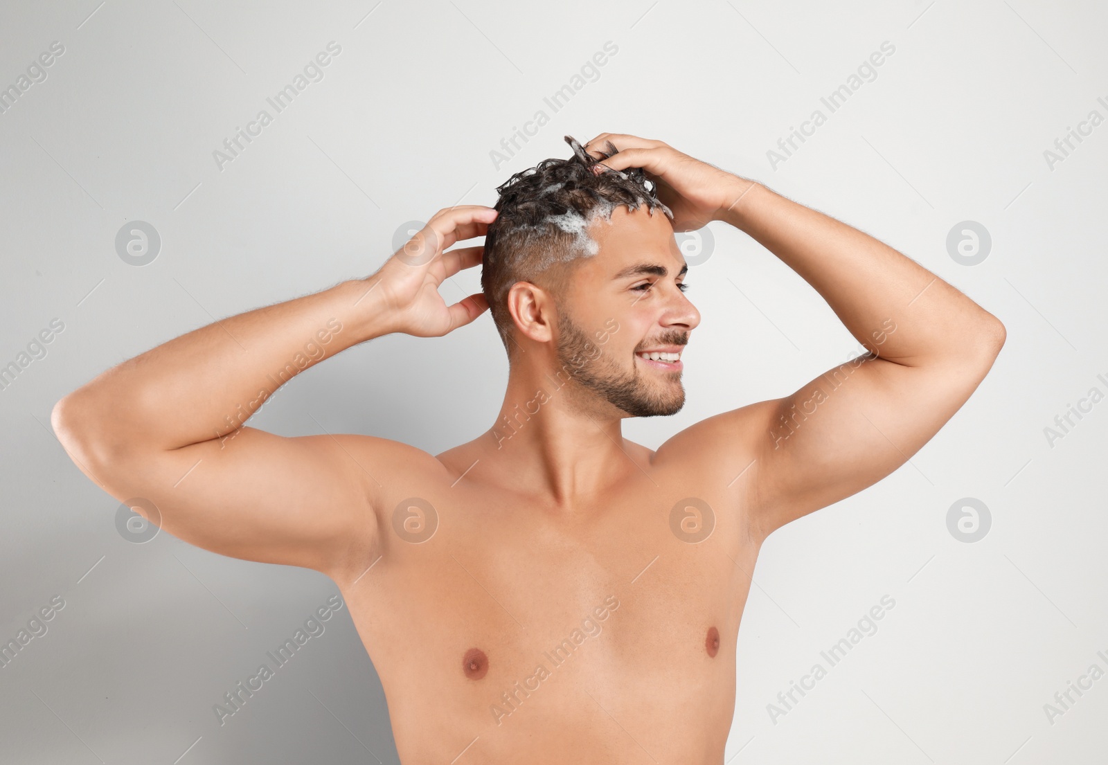 Photo of Young man washing hair on white background