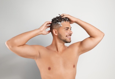 Young man washing hair on white background