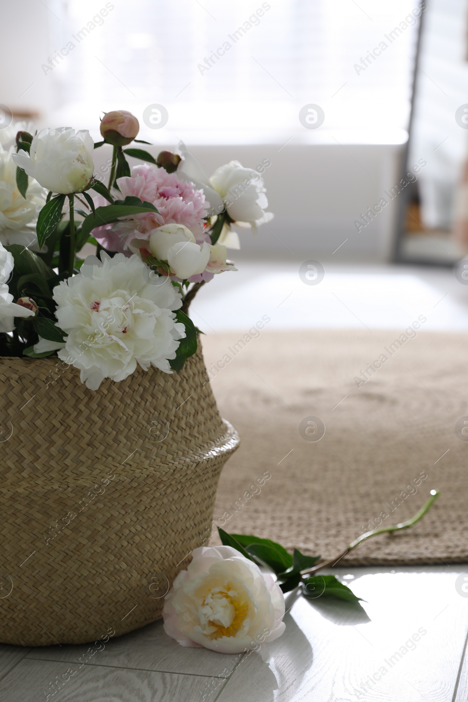 Photo of Bouquet of beautiful peony flowers in basket on floor