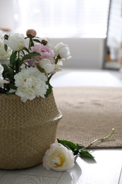 Photo of Bouquet of beautiful peony flowers in basket on floor