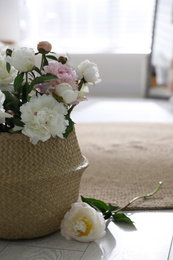 Bouquet of beautiful peony flowers in basket on floor