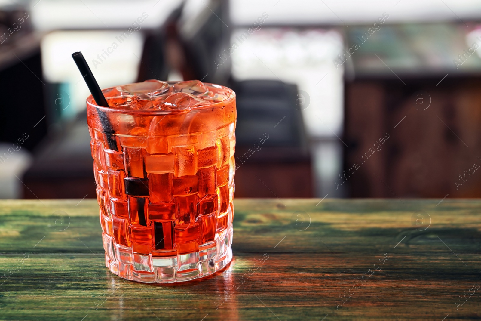 Photo of Glass of delicious cocktail with ice on table in bar