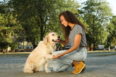 Photo of Young African-American woman and her Golden Retriever dog in park