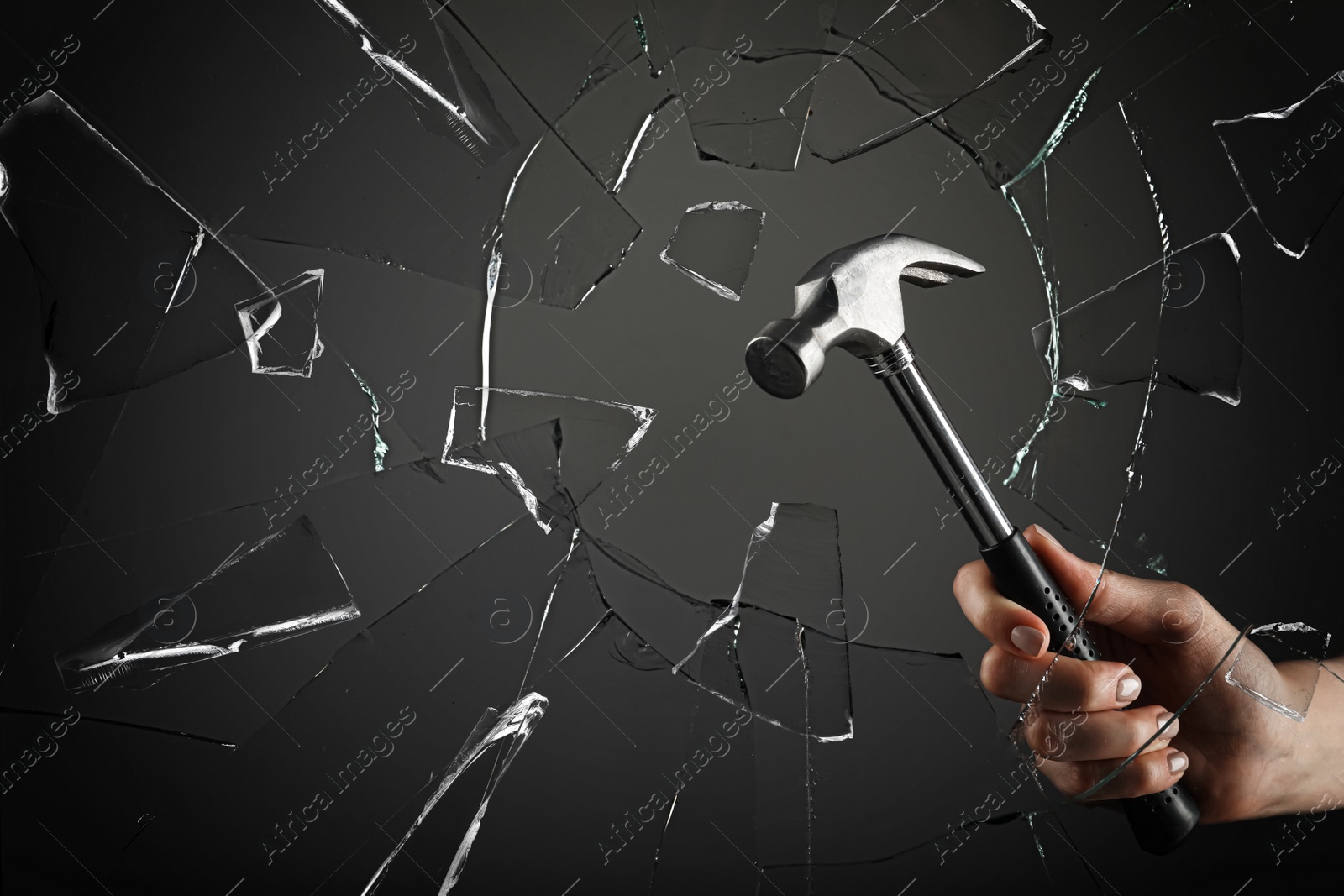 Image of Woman breaking window with hammer on dark grey background, closeup