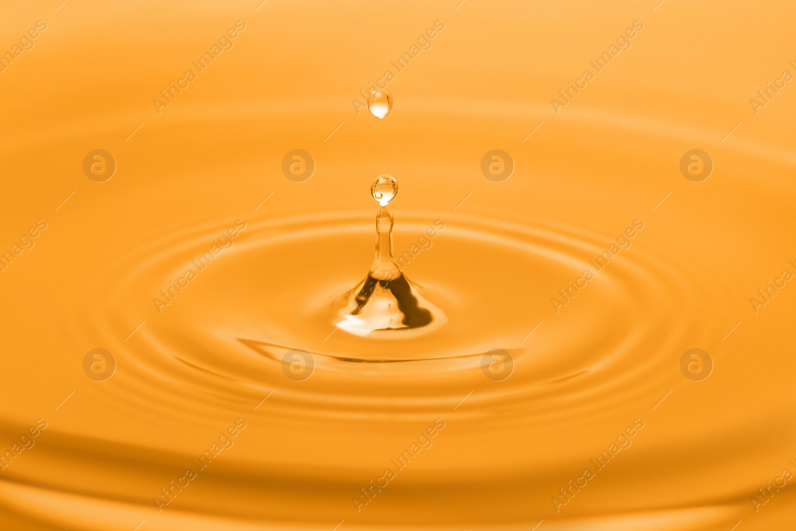 Image of Splash of water with drop, closeup. Toned in orange