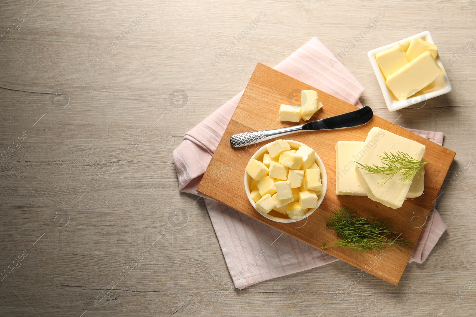 Photo of Tasty butter with dill and knife on wooden table, flat lay. Space for text