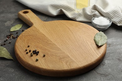 Photo of Cutting board, pepper and bay leaves on grey table. Space for text