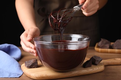 Photo of Woman making delicious chocolate cream at wooden table, closeup