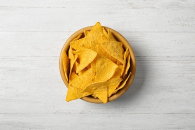 Tasty mexican nachos chips in bowl on white wooden table, top view