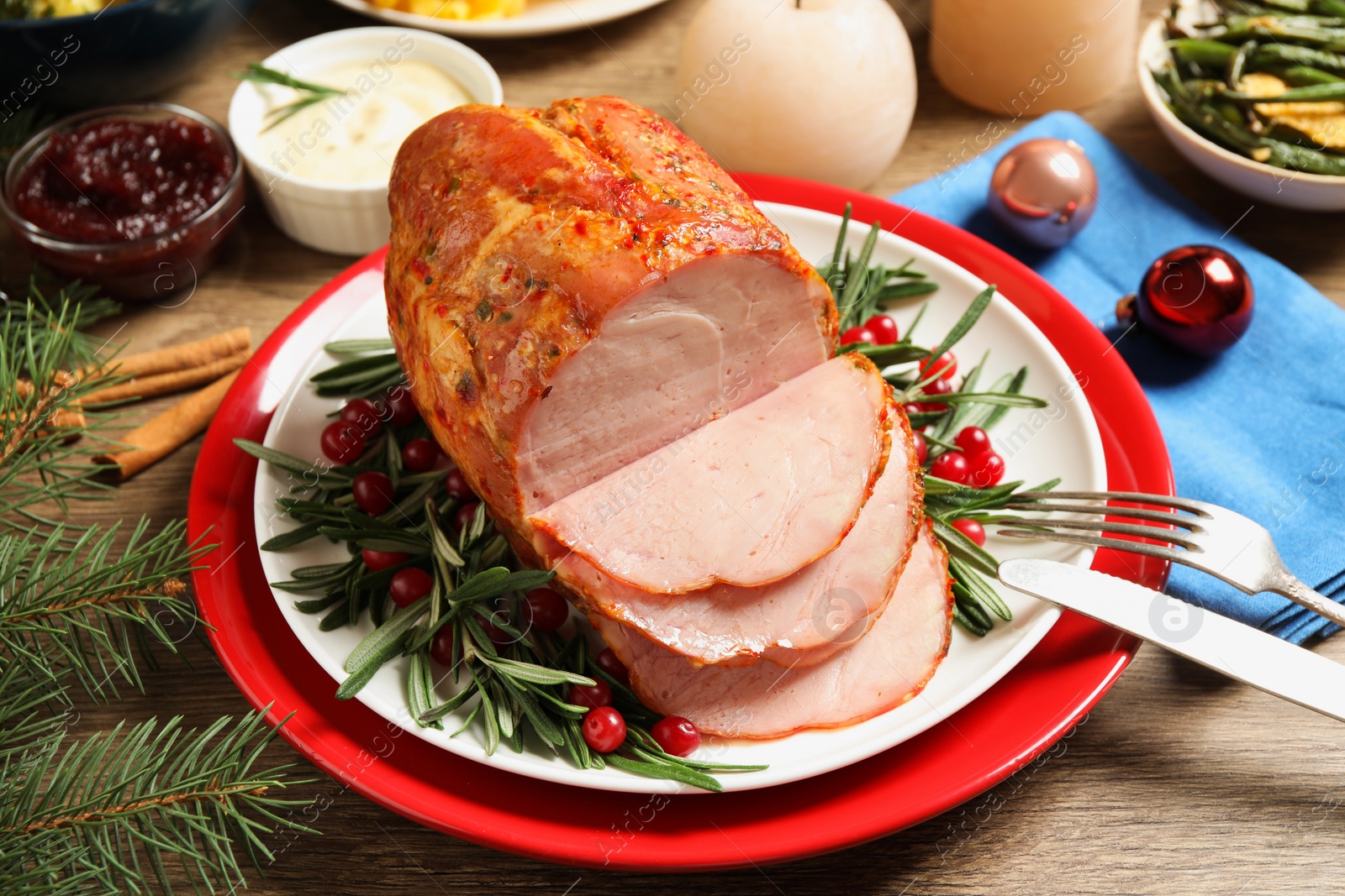 Photo of Delicious Christmas ham served with garnish on wooden table, above view