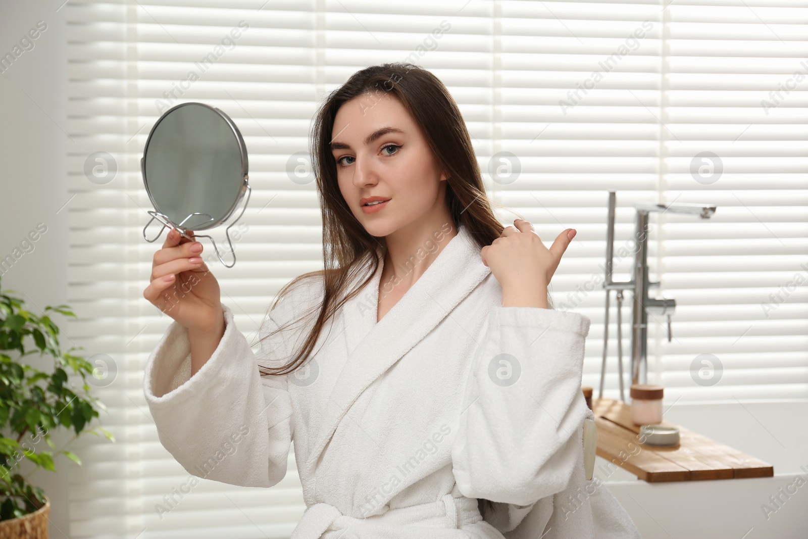 Photo of Beautiful woman looking in mirror in bathroom