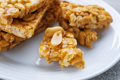 Photo of Delicious peanut kozinaki bars on white plate, closeup
