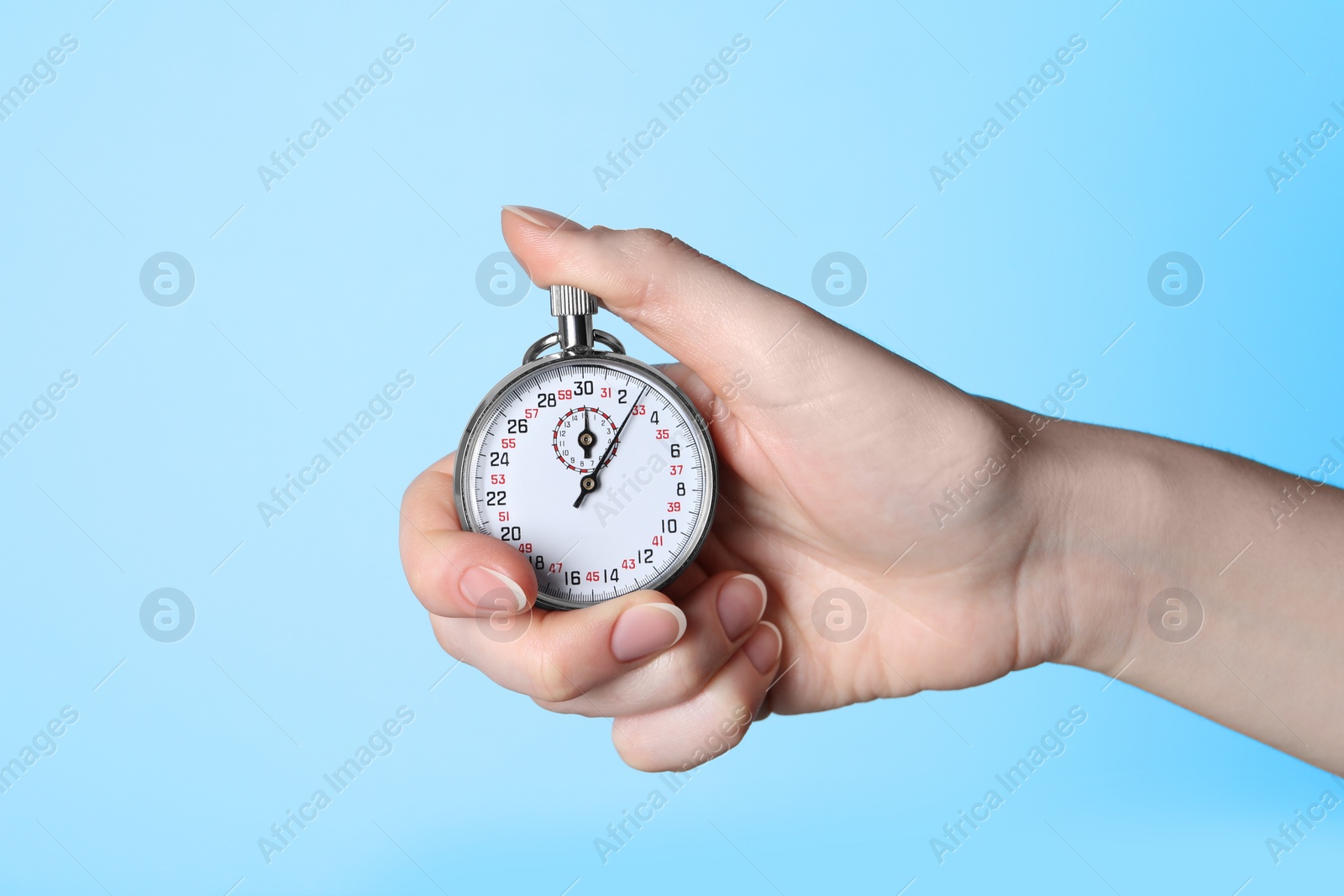 Photo of Woman holding vintage timer on light blue background, closeup