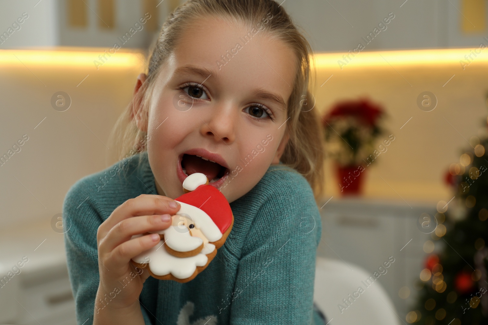 Photo of Cute little girl with Christmas gingerbread cookie at home
