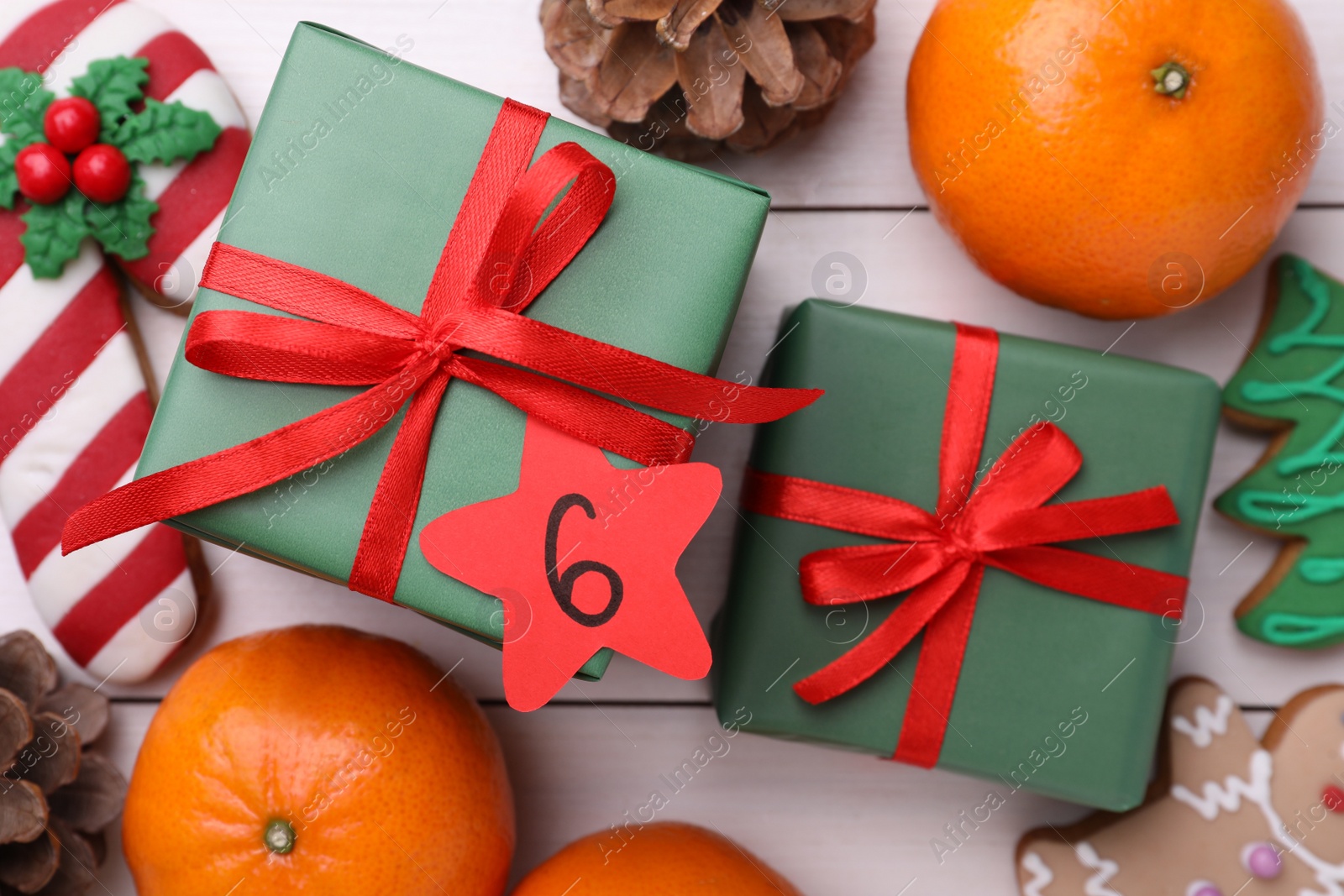 Photo of Gift boxes with paper tag and treats on white wooden background, flat lay. December, 6 - Saint Nicholas Day