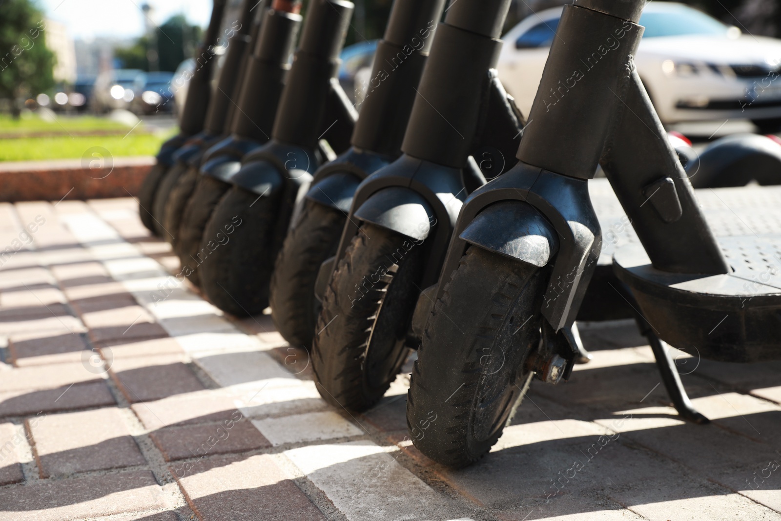 Photo of Many modern electric scooters parked on city street, closeup. Rental service